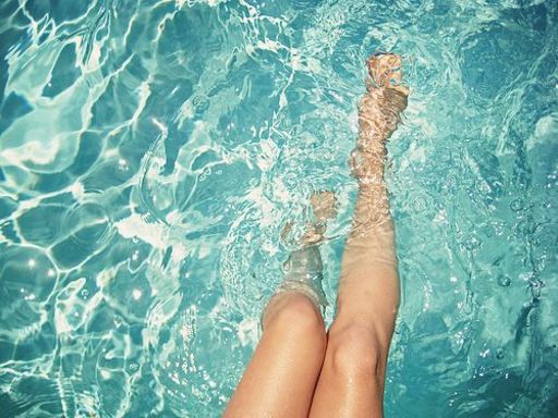 プールに脚を入れる女性の写真