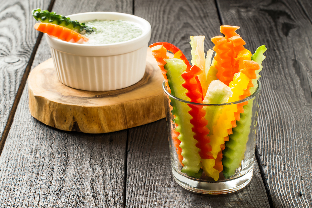 Colorful slices of raw vegetables in glasses (carrots, celery, cucumber, sweet pepper) and yogurt sauce. The concept of diet, healthy and vegetarian food. Selective focus