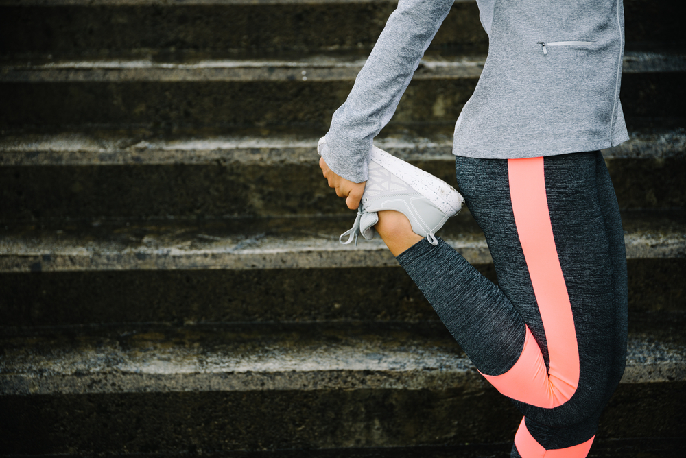 Urban workout and running concept. Woman stretching legs for warming up before exercising and climbing stairs.