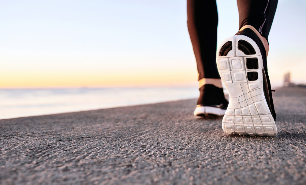Athlete runner feet running on treadmill closeup on shoe. Jogger fitness shoe in the background and open space around him. Runner jogging training workout exercising power walking outdoors in city.