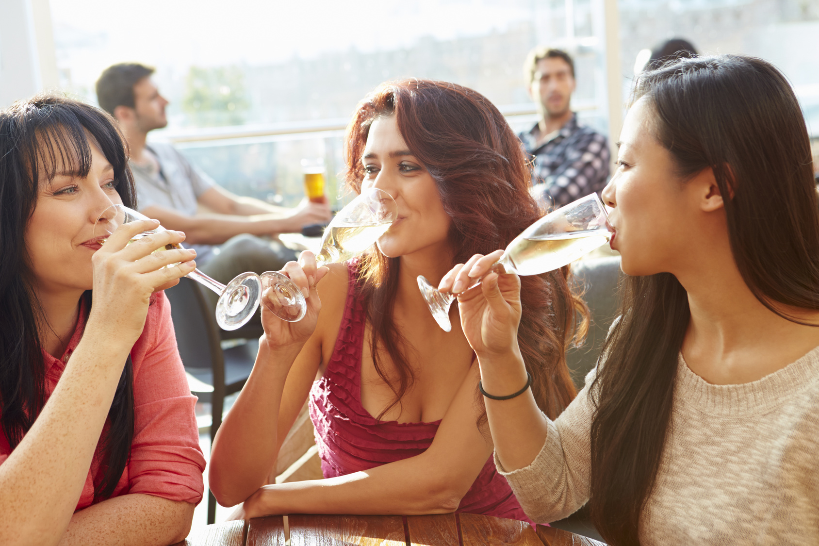 Three Female Friends Enjoying Drink At Outdoor Rooftop Bar